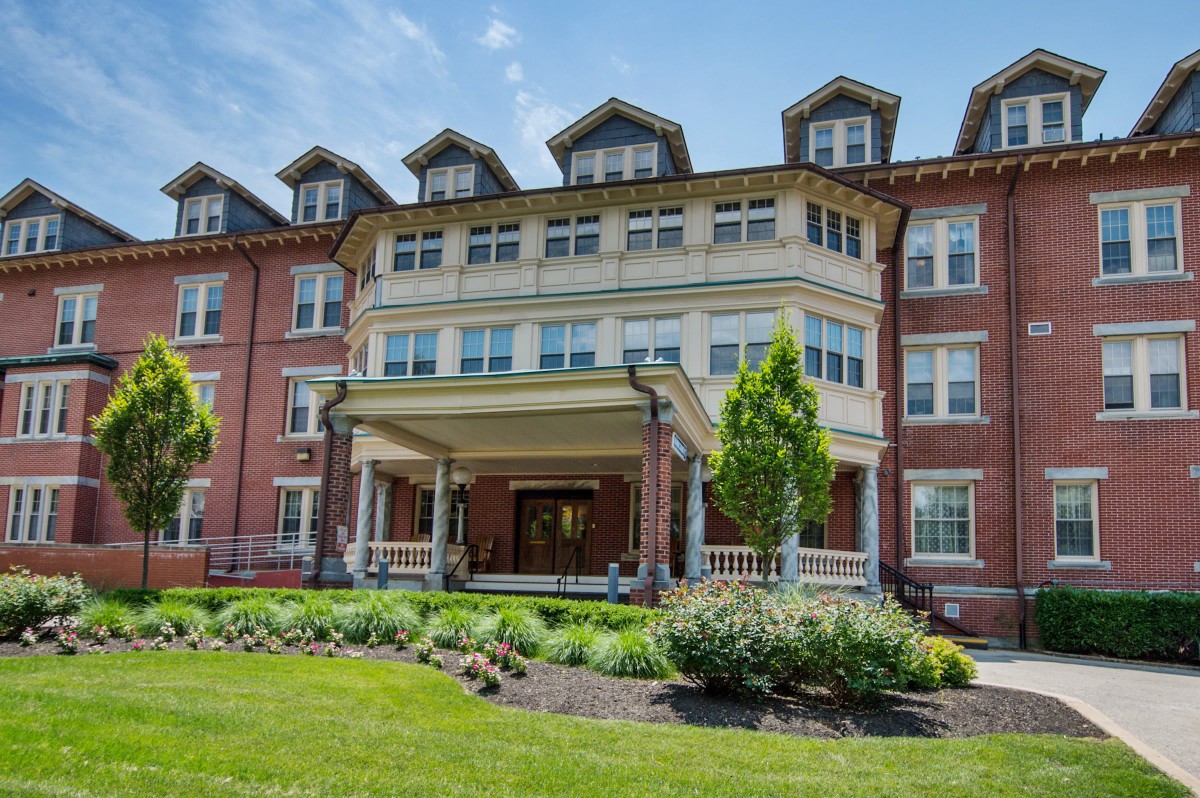 A historic brick building with dormer windows and well-maintained landscaping.