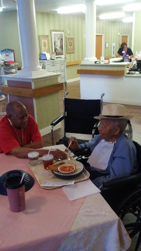 Two elderly individuals sharing a meal and enjoying each other's company in a care facility.