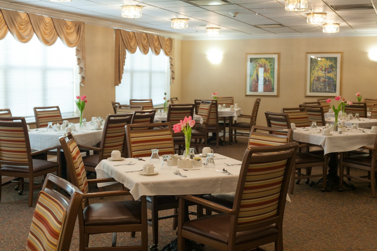An elegant dining room with neatly arranged tables and chairs, adorned with flowers.