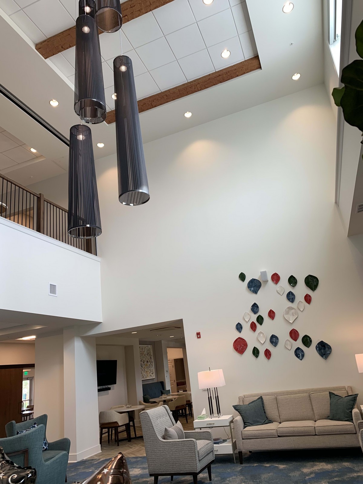 A modern lobby with high ceilings, pendant lighting, and colorful wall art.