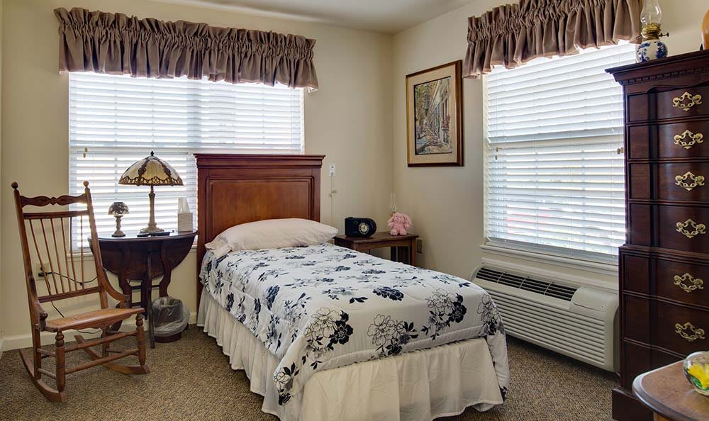A cozy bedroom with a single bed, floral bedding, and window curtains.