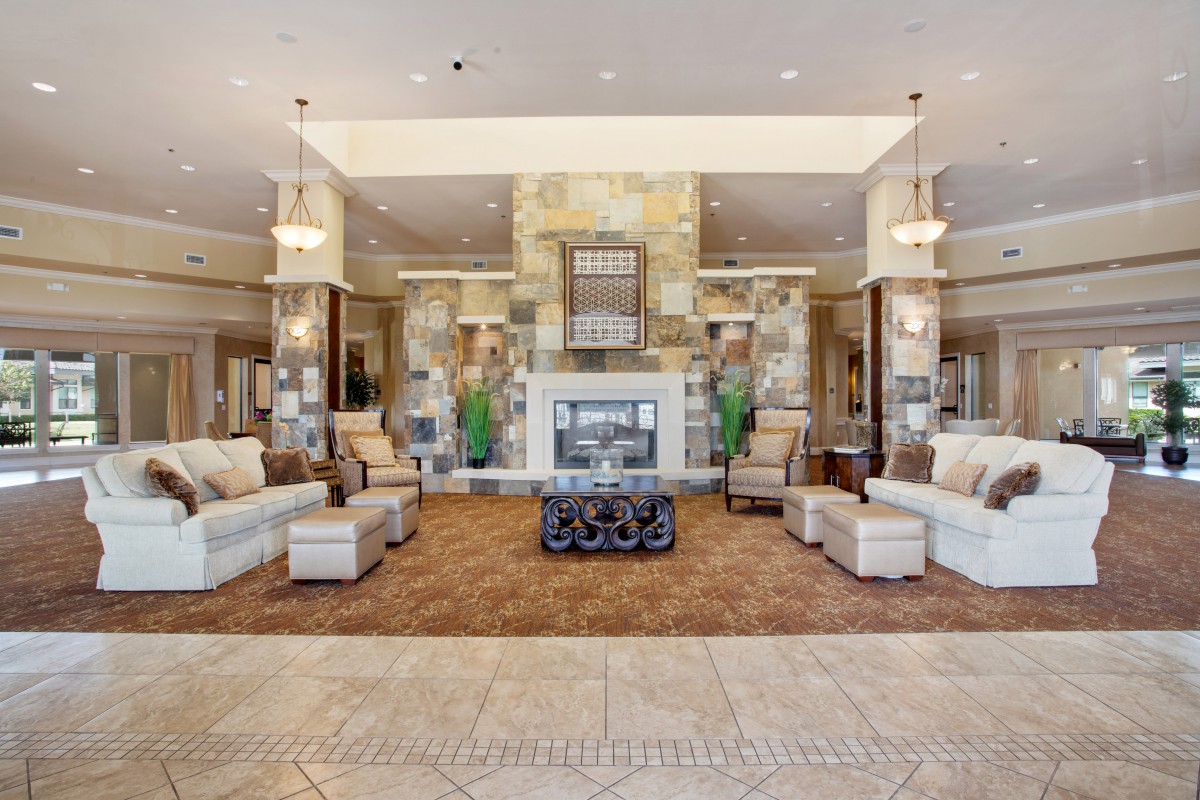 A spacious and elegantly decorated lobby featuring a central fireplace, comfortable seating, and stylish lighting.