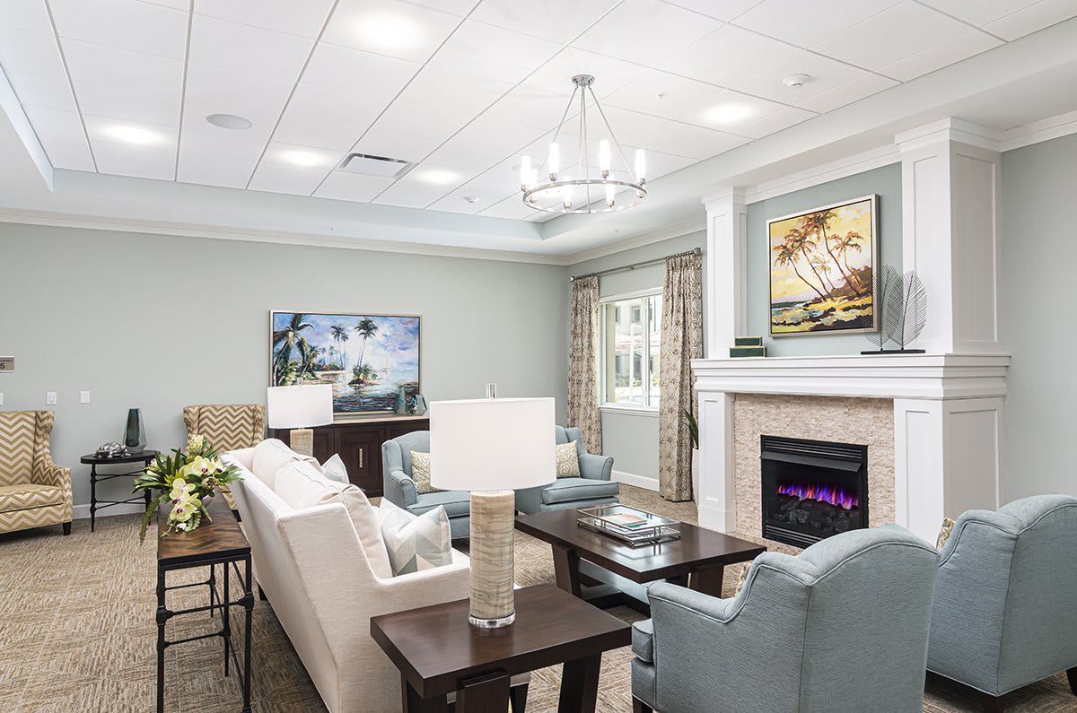 A modern living room with elegant decor, featuring a sofa, chairs, a fireplace, and a chandelier.