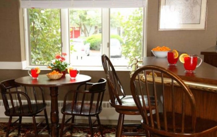 A cozy dining area with wooden tables and chairs, accented by natural light and plants.