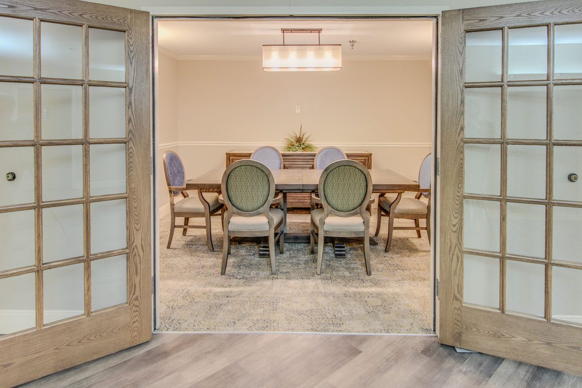 A well-appointed dining room with a large table and elegant chairs, accented by a chandelier above.