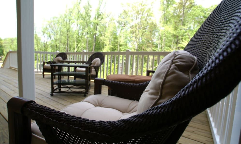 A cozy outdoor patio with wicker furniture surrounded by lush trees.