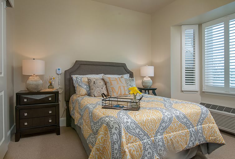 A cozy bedroom featuring a neatly made bed with patterned bedding and two bedside lamps.