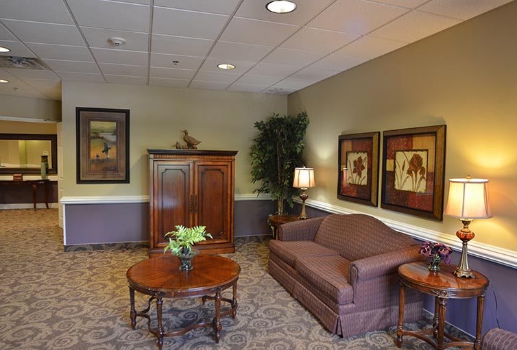 A cozy living room with a sofa, coffee table, and cabinet adorned with artwork and plants.