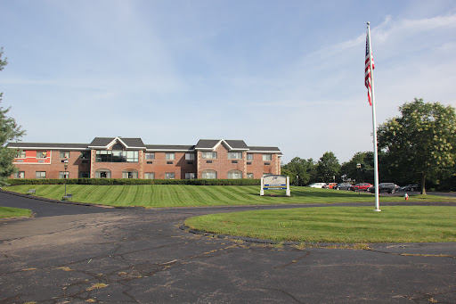 A view of a residential building with a flag in the foreground and well-maintained grass.