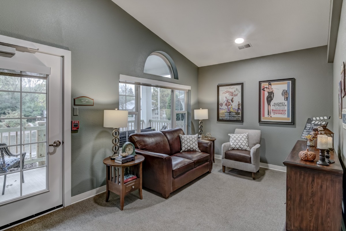 A cozy living room with a leather sofa, armchair, and decorative wall art.