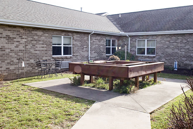 A courtyard featuring a raised garden bed and patio furniture surrounded by a brick building.
