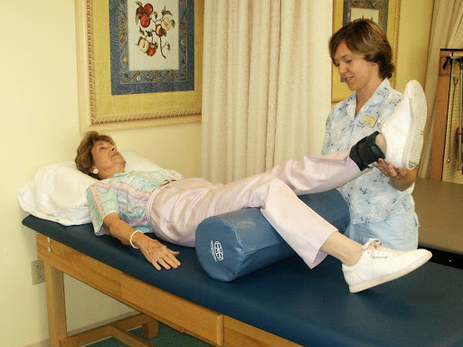 A physical therapist assists a patient with leg exercises during a rehabilitation session.