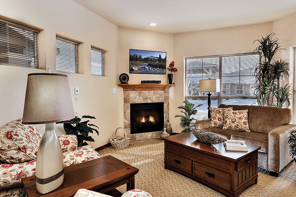 A cozy and well-decorated living room featuring a fireplace, comfortable furniture, and large windows.
