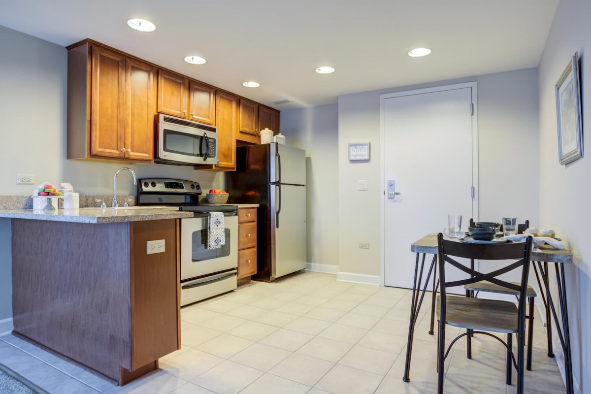 A modern kitchen in an apartment with stainless steel appliances and wooden cabinets.