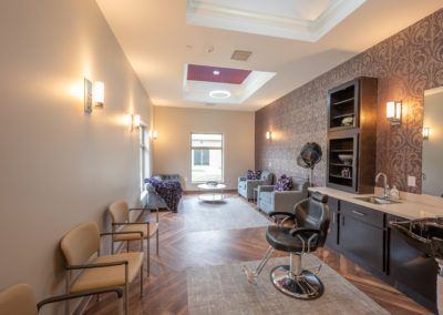 A modern salon interior featuring a seating area with chairs and a hair dryer station.
