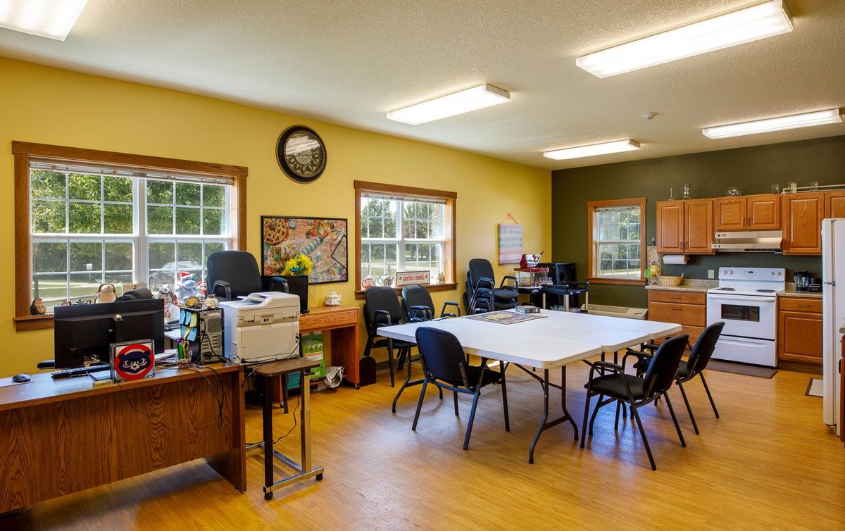 A spacious office with tables and chairs, featuring computers and large windows.