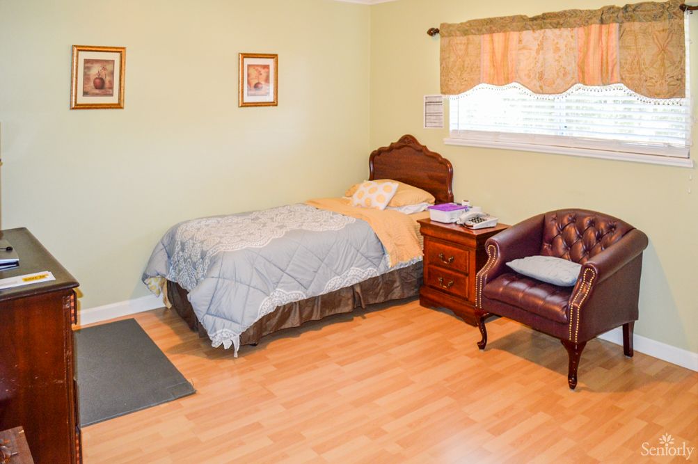 A cozy bedroom with a single bed, wooden furniture, and a window.