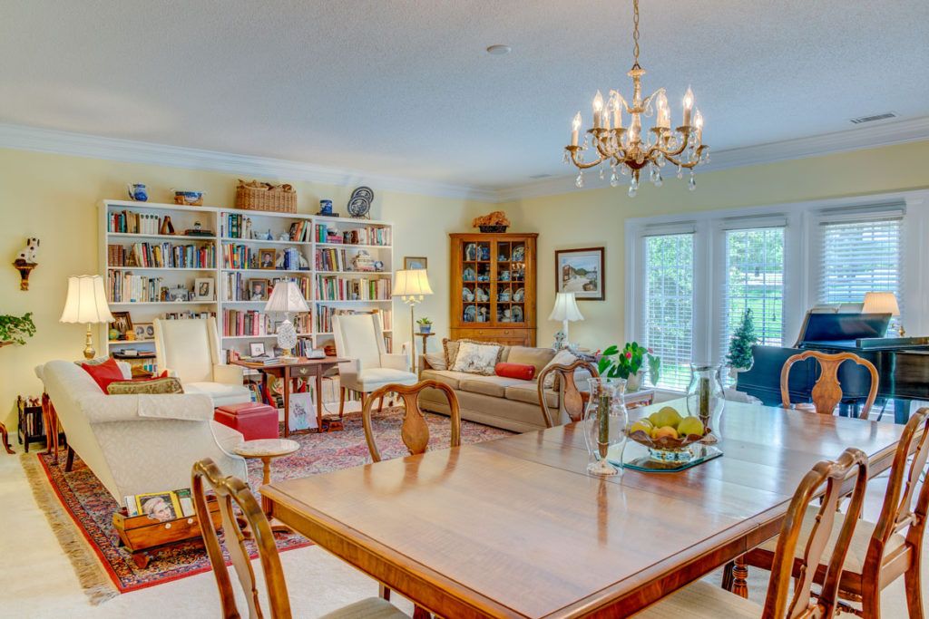 A cozy living and dining area featuring a chandelier, bookshelves, and stylish furniture.
