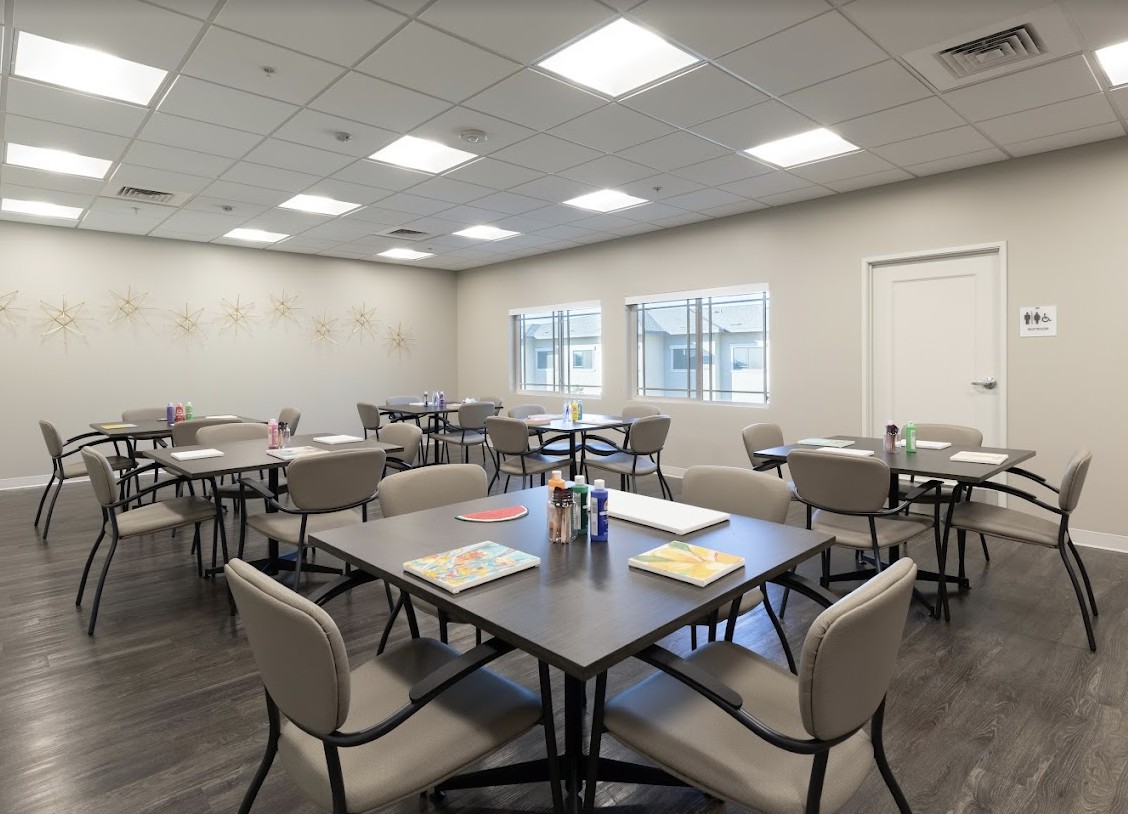 A well-lit classroom setup with tables and chairs, featuring documents on the tables.