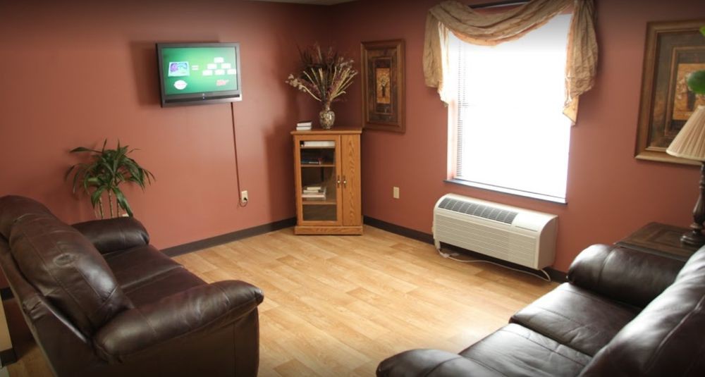 A cozy living room with a wall-mounted television, cabinet, and sofa on a wooden floor.
