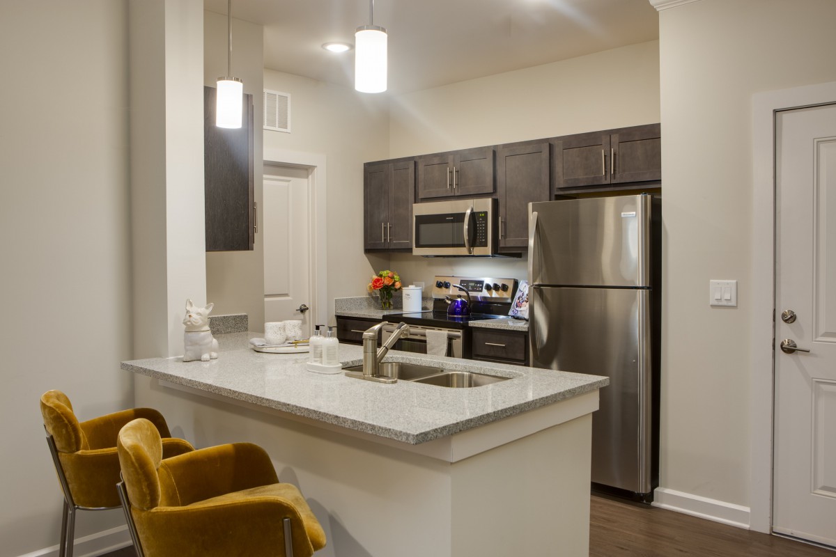 A modern kitchen with stainless steel appliances and elegant pendant lighting.