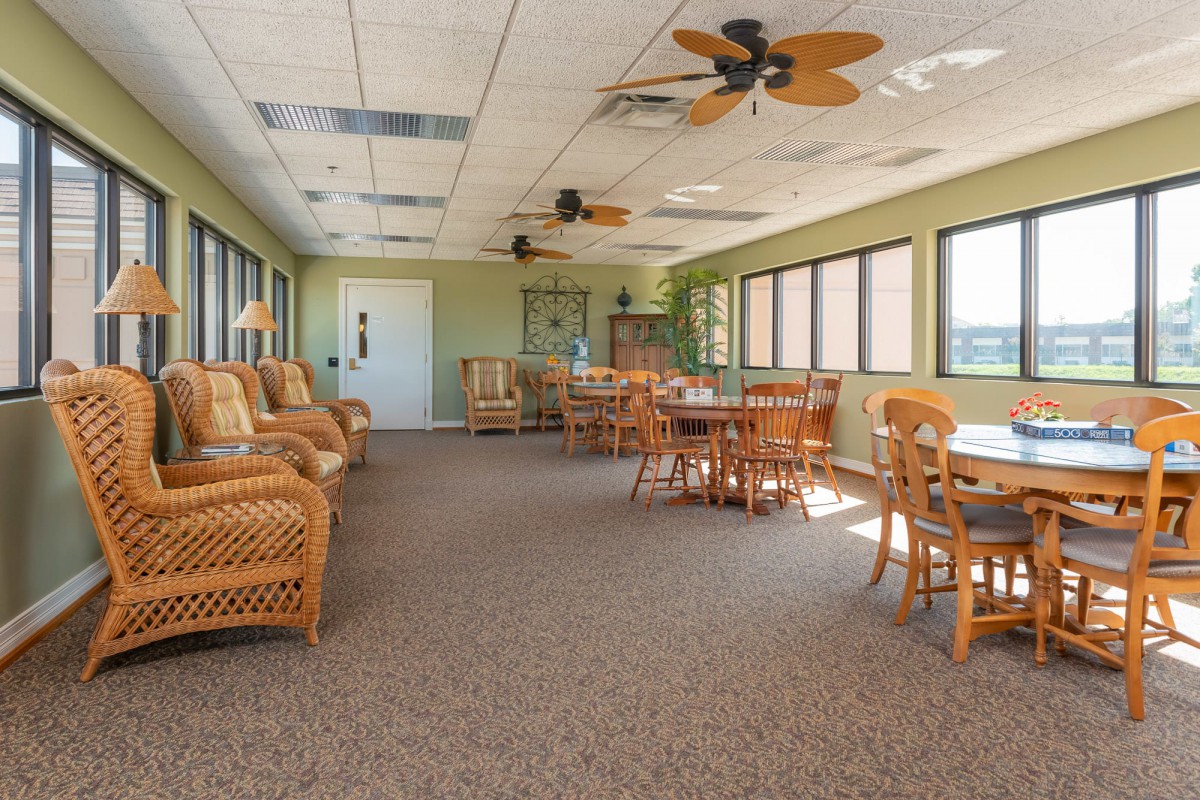 A spacious indoor seating area with wicker furniture and large windows letting in natural light.