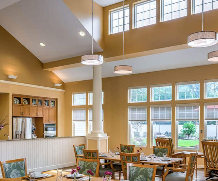 A well-lit dining area with tables and chairs, enhanced by large windows allowing natural light to fill the space.
