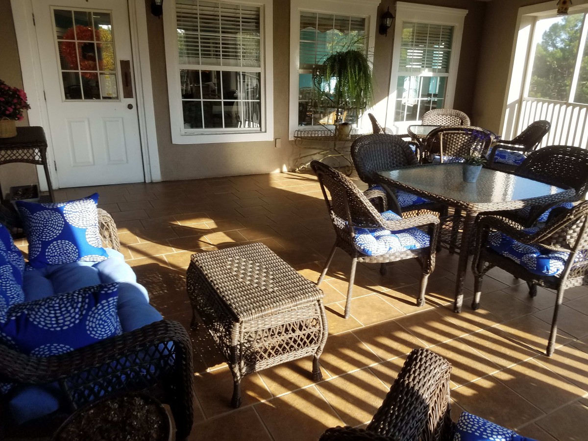 A cozy outdoor patio area with comfortable seating and a table, bathed in warm sunlight.
