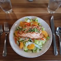 A plate of salmon salad served with fresh vegetables and citrus slices.