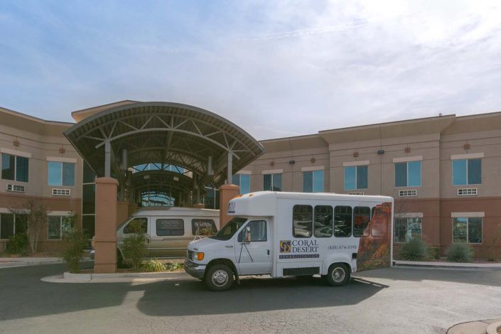 A shuttle bus parked outside a hospital entrance on a sunny day.