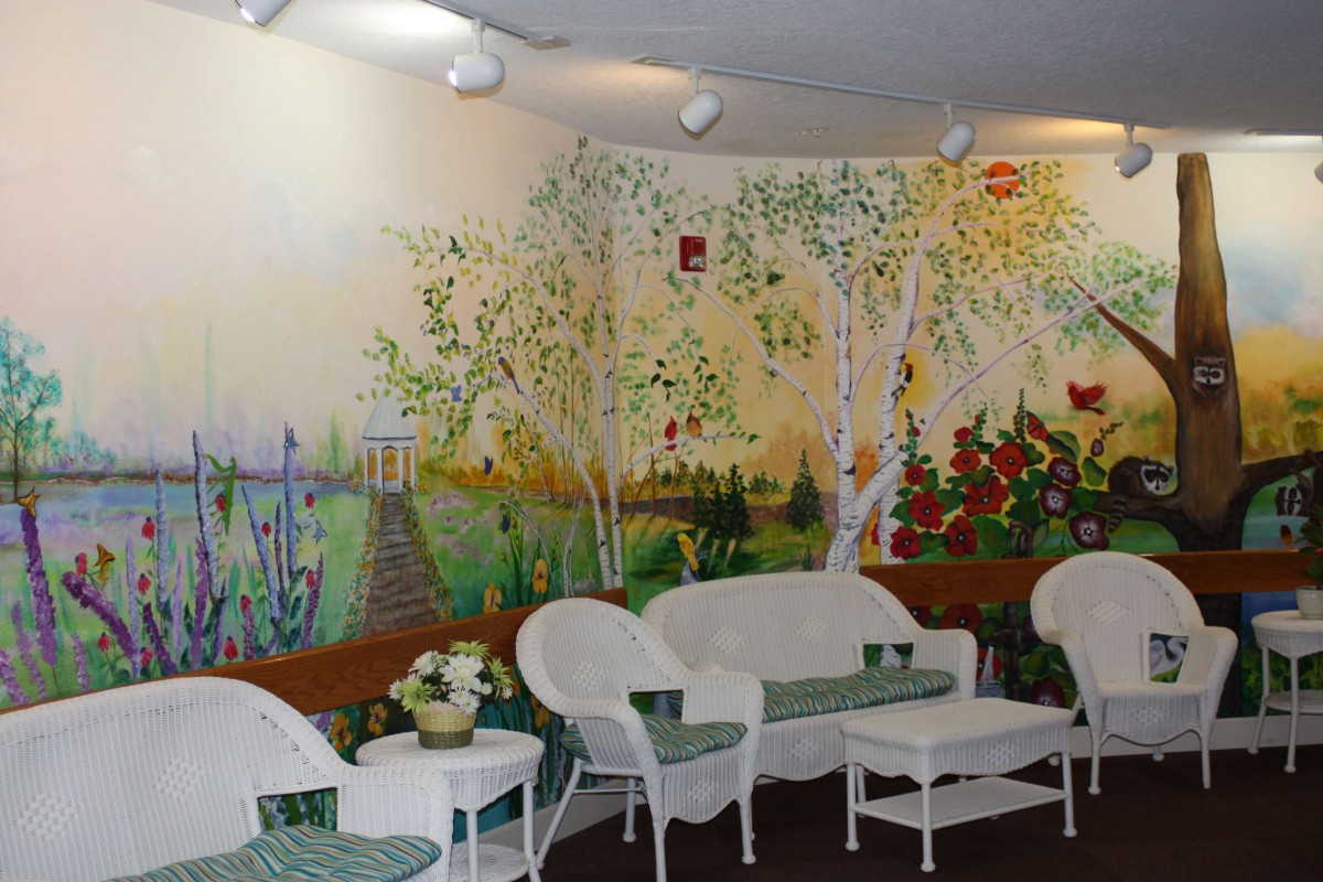 A cozy indoor seating area featuring wicker furniture and a vibrant nature-themed mural on the wall.