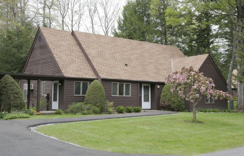 A suburban house with a well-maintained lawn and surrounding trees.
