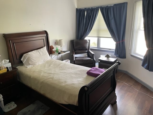 A cozy bedroom with a single bed and an armchair by the window.