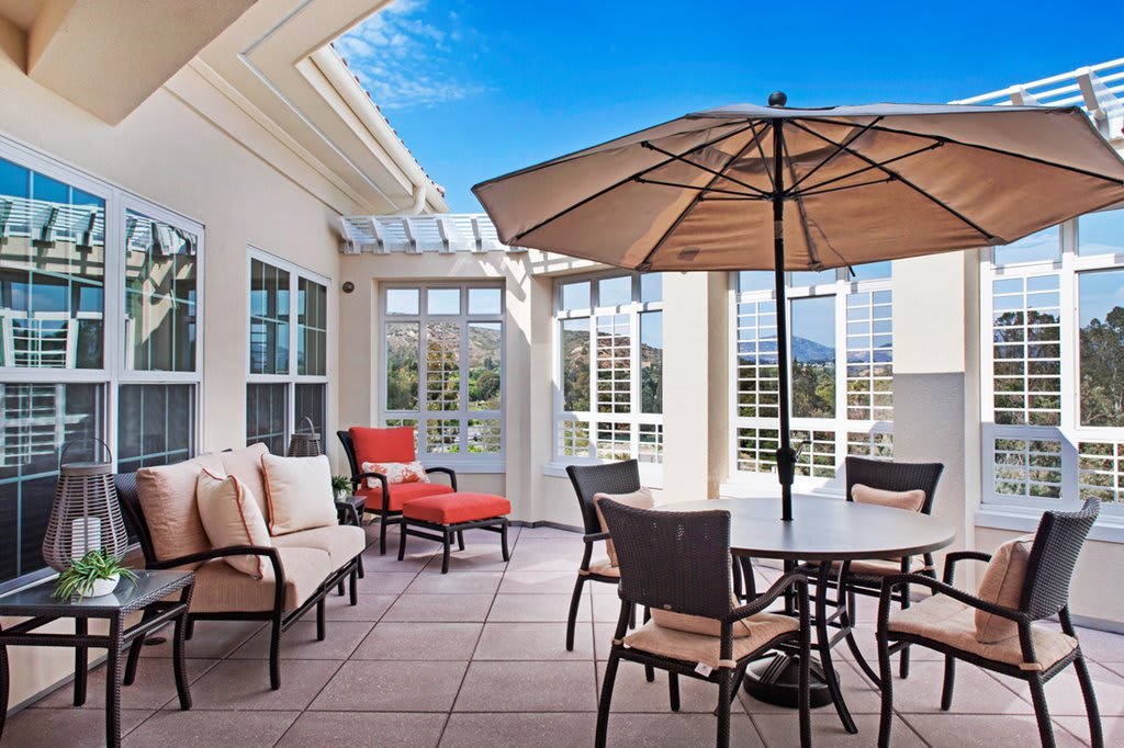 A sunny patio featuring outdoor furniture with an umbrella, offering a scenic view.