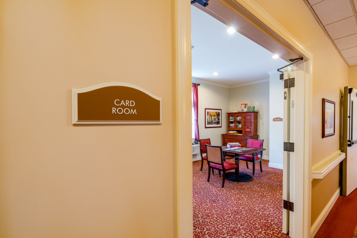 An inviting card room with a table and chairs visible through an open door.