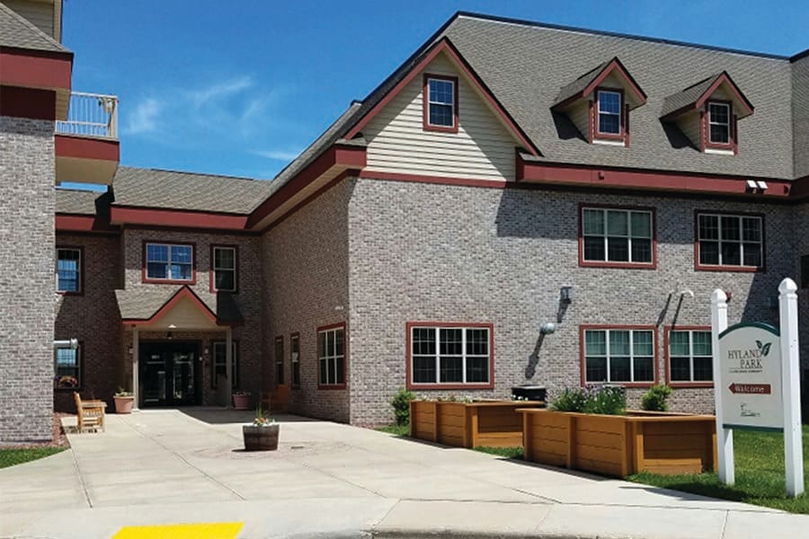 A two-story residential building with a brick exterior and several windows under a clear blue sky.