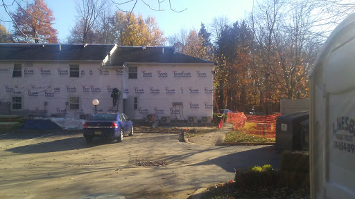 A house under renovation during the autumn season, with construction workers present.