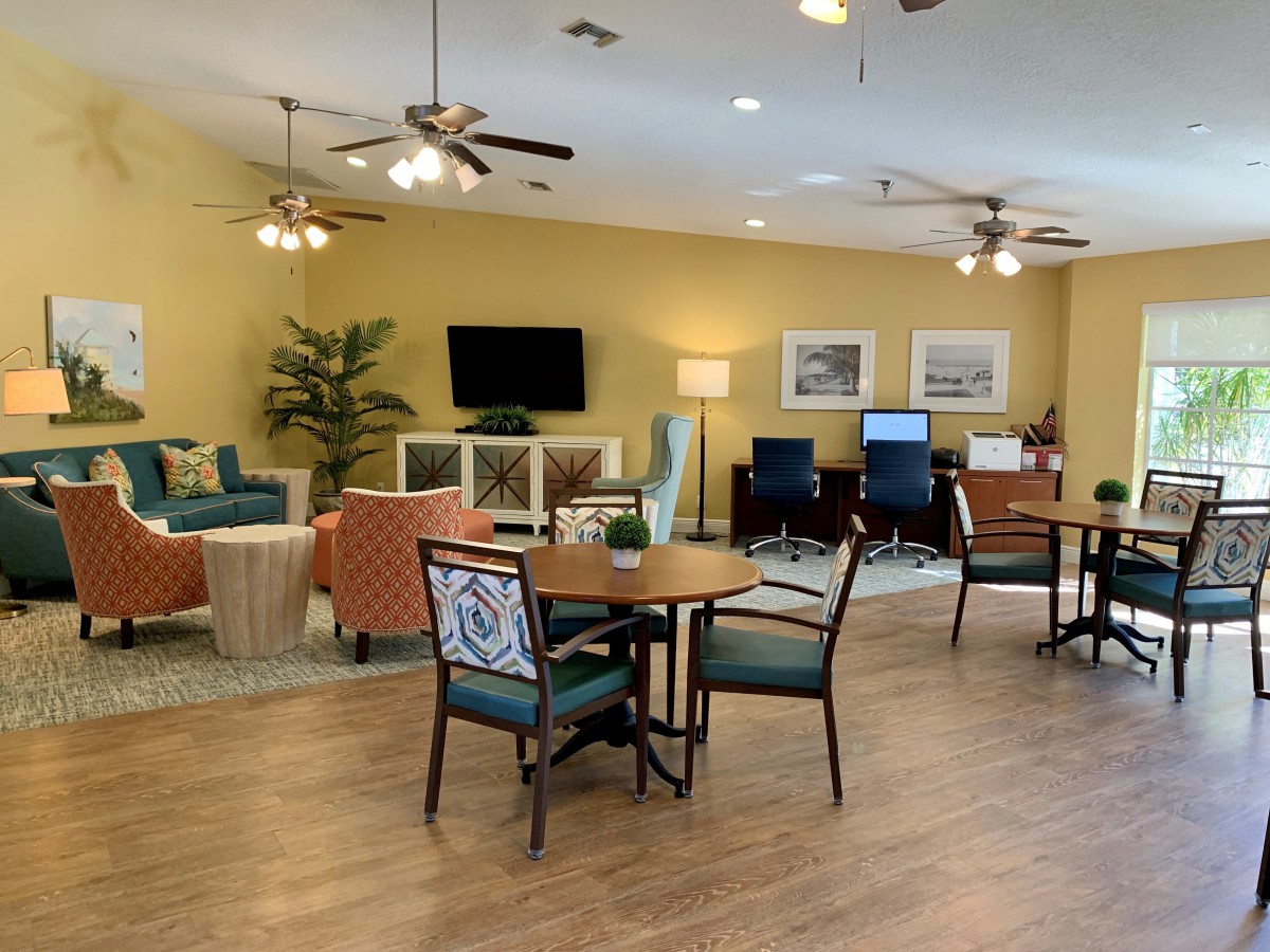 A cozy lounge with comfortable seating and a television, decorated with plants and artwork.