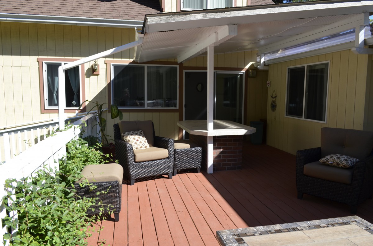 A cozy outdoor patio with wicker furniture and a covered deck.