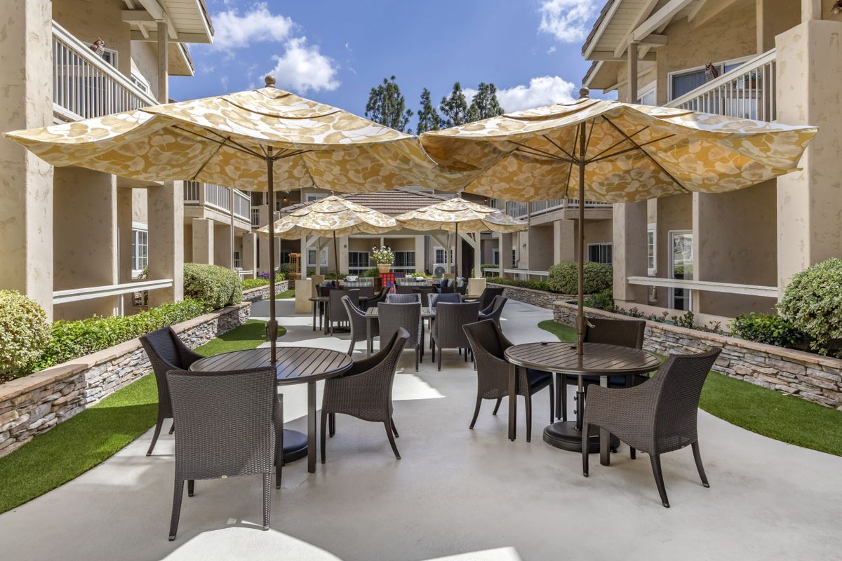 An inviting courtyard with tables and chairs shaded by large umbrellas.
