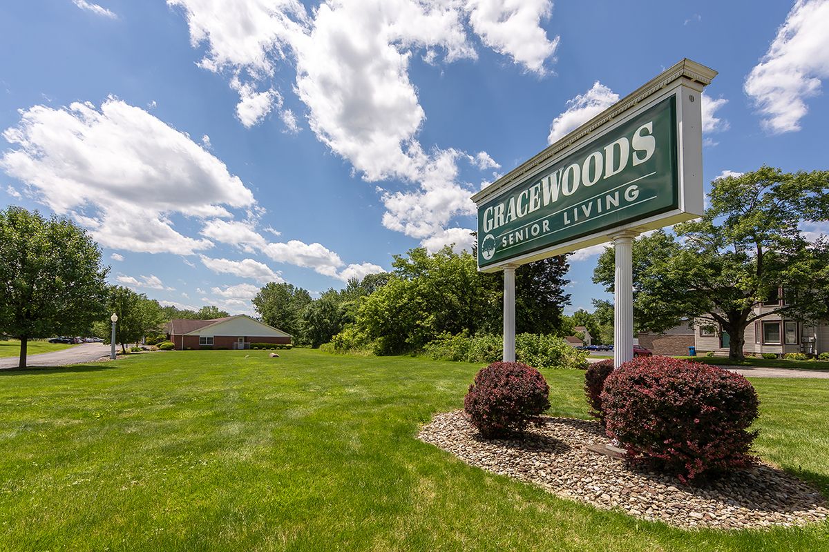 A scenic view of a park with a sign reading 'Lakewoods Senior Living'.