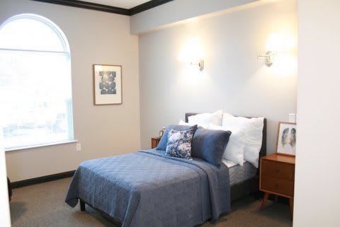 A cozy bedroom with a neatly made bed, bedside tables, and wall-mounted lamps.