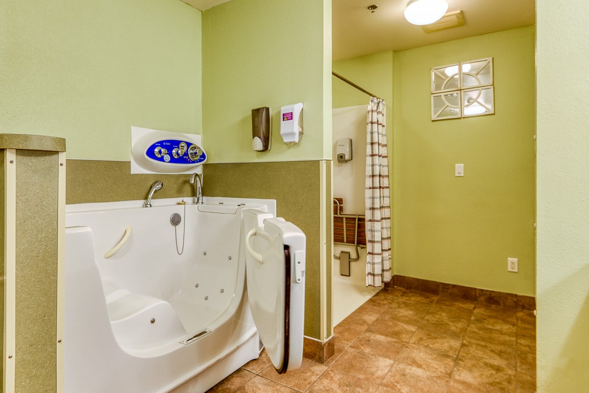 A bathroom featuring a walk-in bathtub and a separate shower area with a tiled floor.