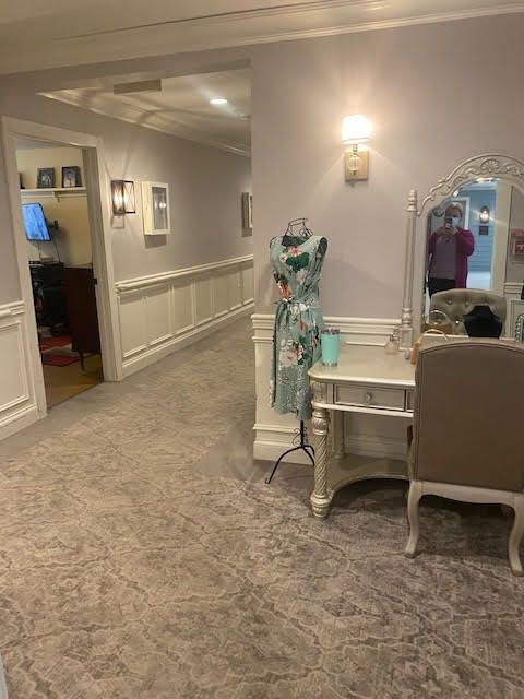 A decorated hallway with a vanity, mannequin displaying a dress, and elegant lighting.
