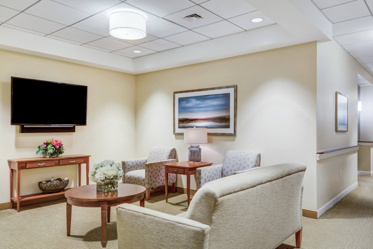 A cozy waiting room with comfortable seating, a television, and wall art.