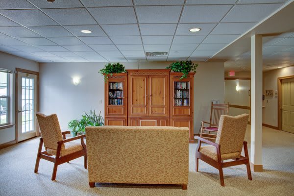 A cozy waiting room with a sofa, chairs, and a wooden cabinet.