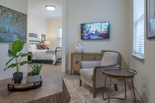 A cozy living room with a view into an adjacent bedroom, featuring modern furniture and decor.