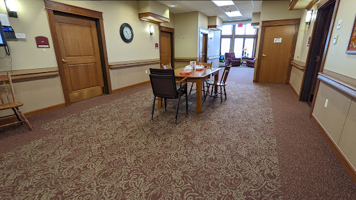 A spacious interior room featuring a table and chairs on a patterned carpet, with doors leading to other areas.