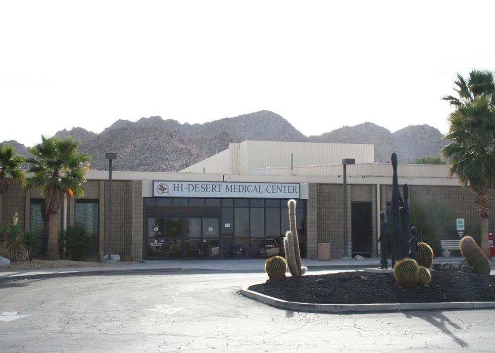 The exterior of a museum with sculptures in the foreground, set against a mountainous desert backdrop.