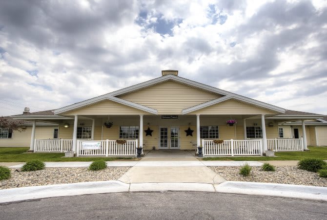 A single-story building with a large porch and cloudy sky overhead.